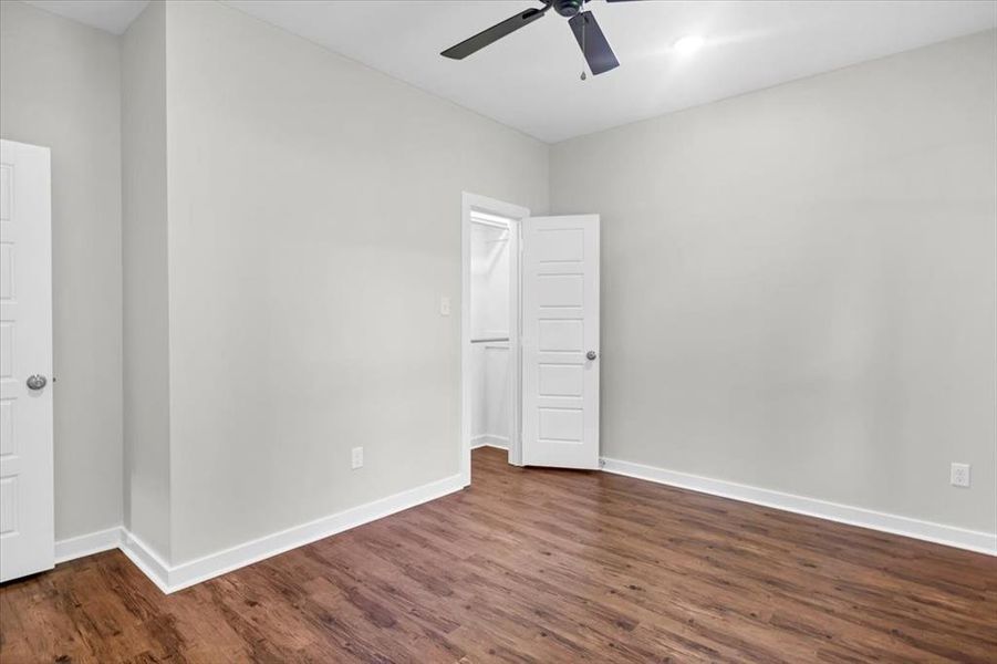 Empty room with dark wood-style flooring, baseboards, and ceiling fan