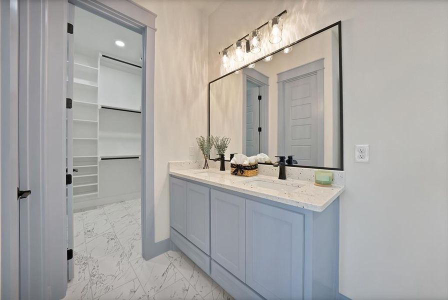 Bathroom with light marble finish floors, double vanity, a spacious closet, and recessed lighting