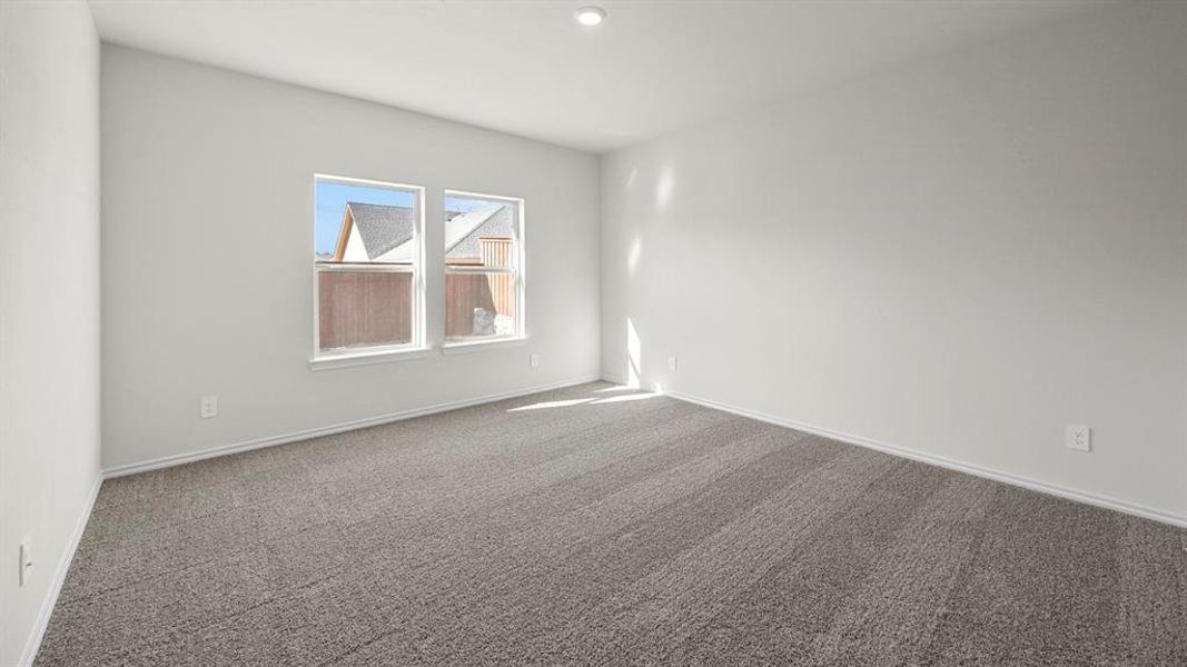 Spare room featuring dark carpet and baseboards
