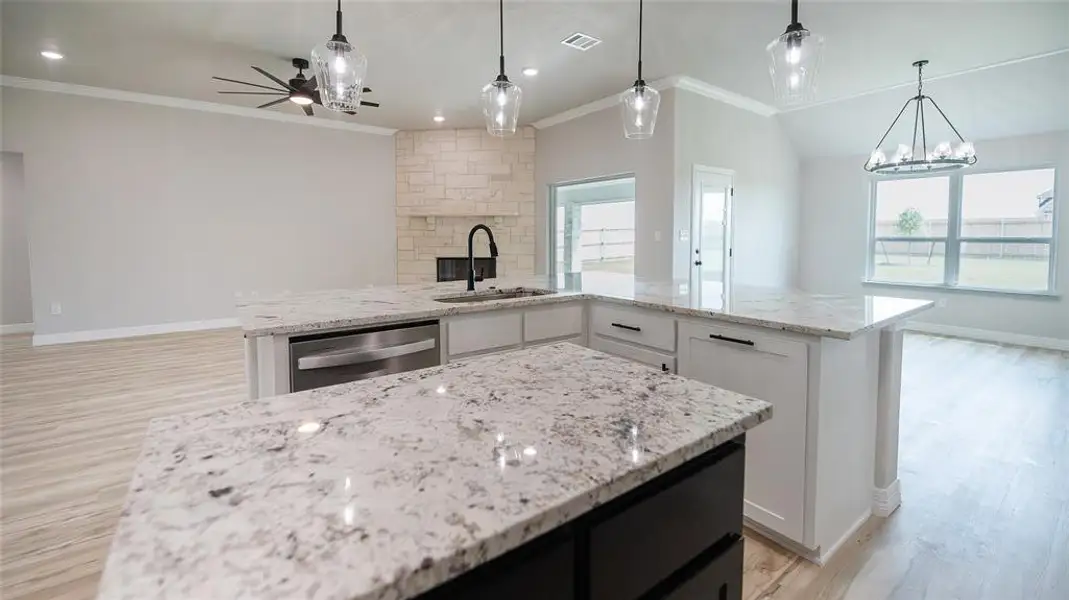 Kitchen with crown molding, a kitchen island, ceiling fan, dishwasher, and light stone countertops Kitchen with crown molding, a kitchen island, ceiling fan, dishwasher, and light stone countertops