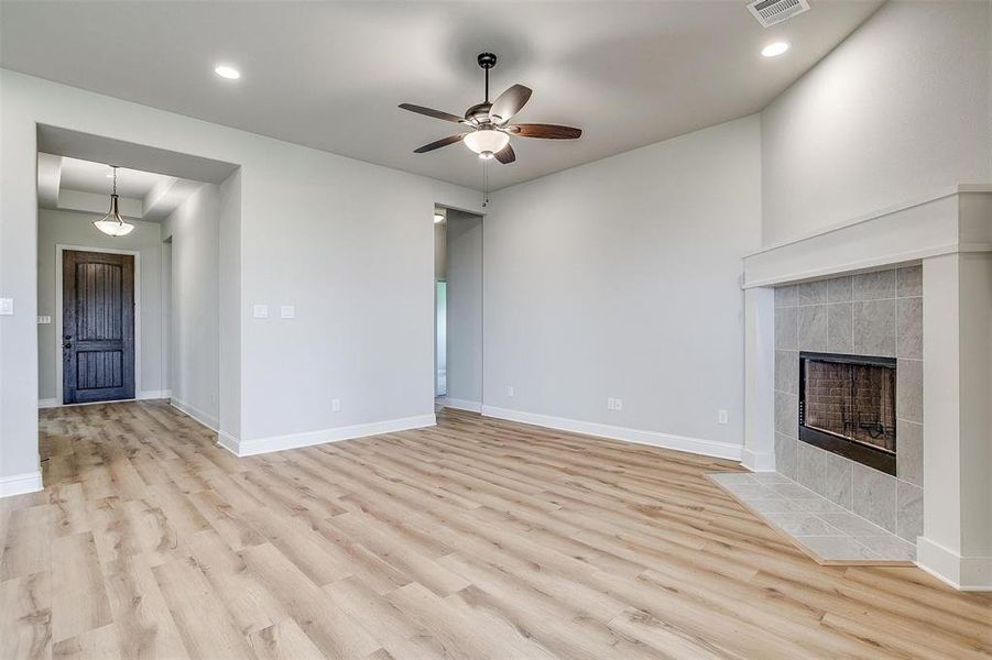 Unfurnished living room featuring light hardwood / wood-style floors, a tile fireplace, and ceiling fan