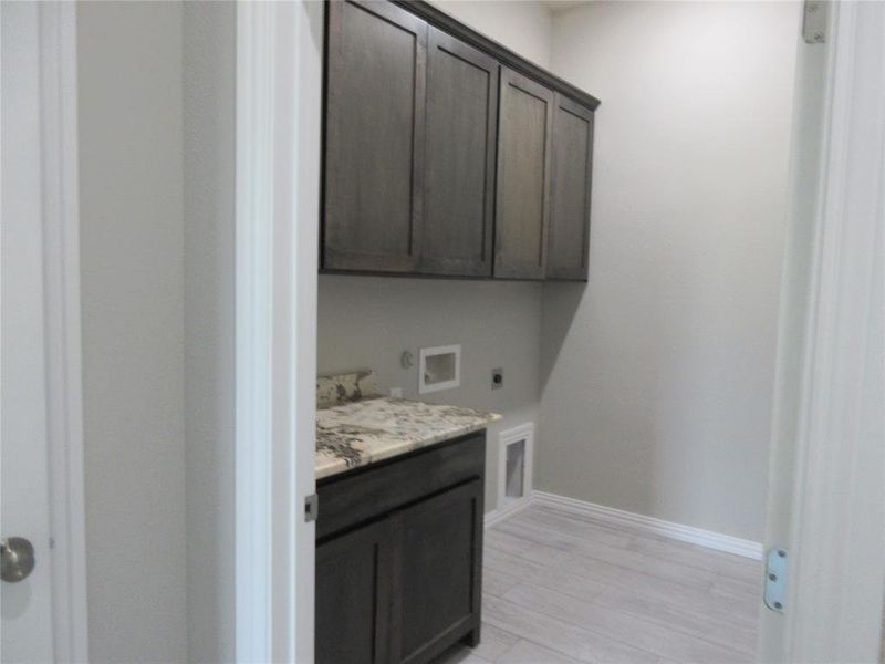 Laundry room with washer hookup, hookup for an electric dryer, light wood-type flooring, and cabinets