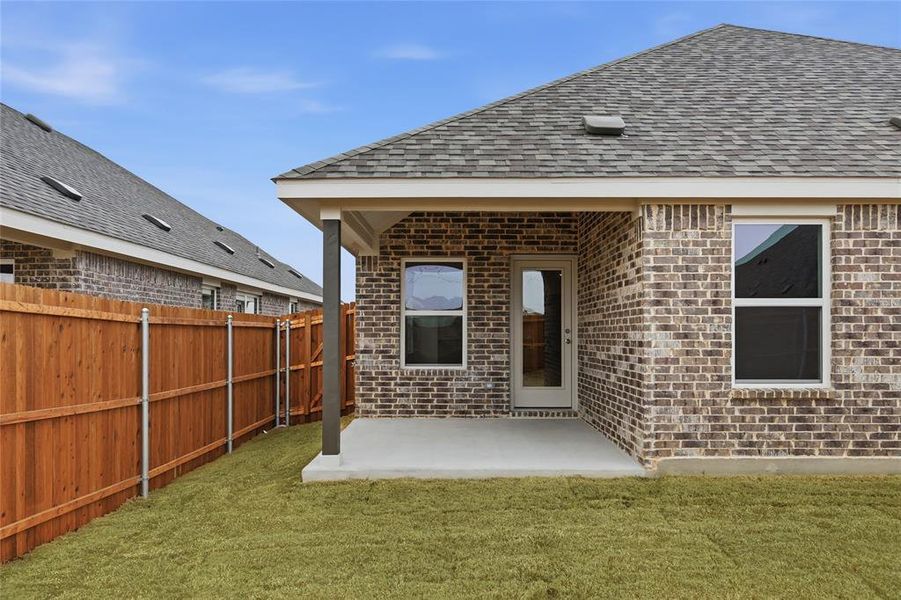 Back of house featuring a patio area, brick siding, and a shingled roof