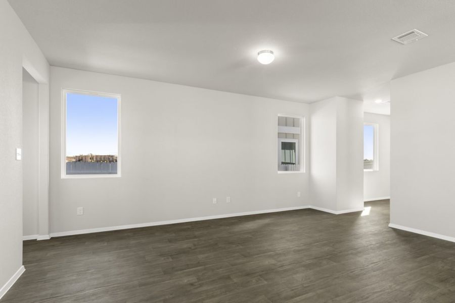 Image of a living room with light grey walls, dark brown vinyl flooring, two windows and white trim