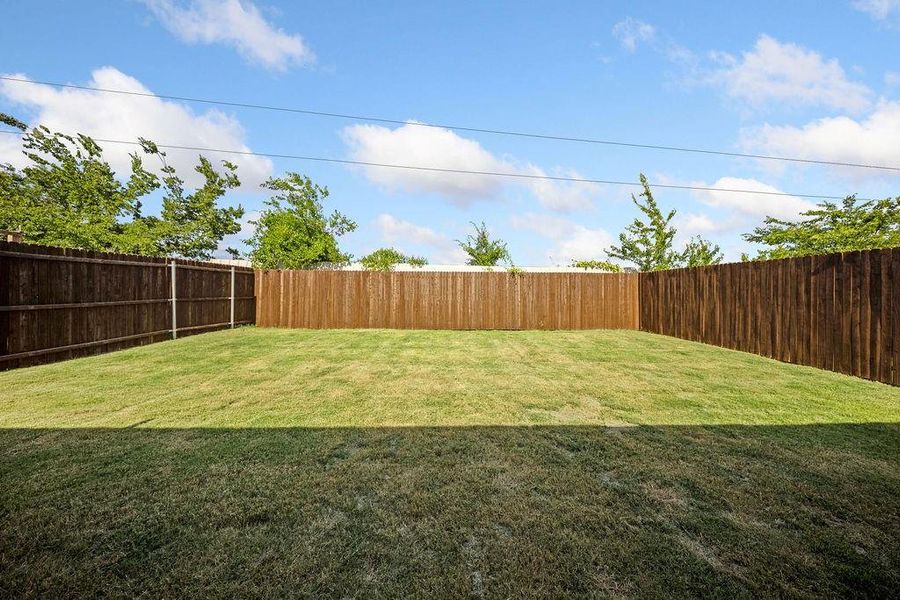 Expansive backyard featuring a manicured lawn, full wood fencing, and mature perimeter trees Expansive backyard featuring a manicured lawn, full wood fencing, and mature perimeter trees