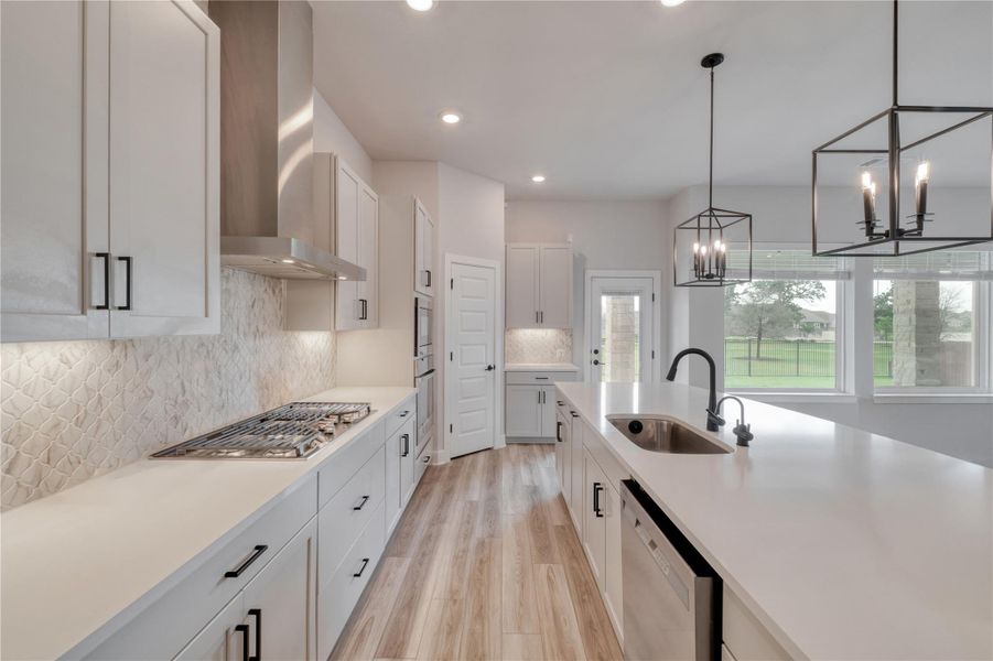 Modern kitchen featuring light-toned cabinetry, quartz countertops, and wood-finish flooring