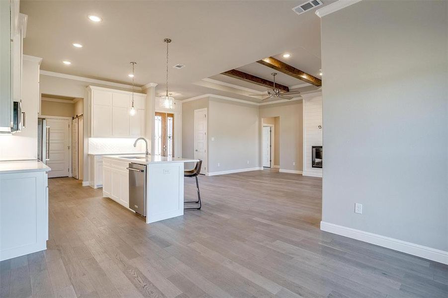 Kitchen featuring hanging light fixtures, white cabinetry, a kitchen island with sink, and sink