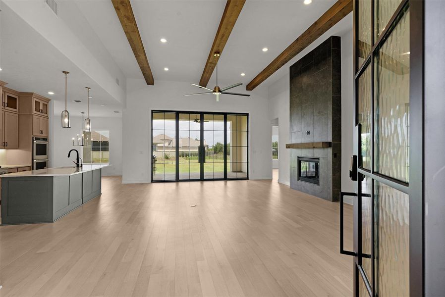 Exposed wood beams crown an airy living space with a commanding fireplace and sliding glass doors.