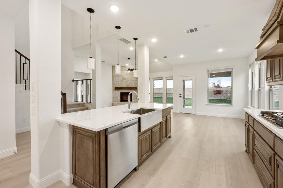 Kitchen with large island, farmhouse sink, dark wood cabinets, pendant lights, and open view to living area with fireplace Kitchen with large island, farmhouse sink, dark wood cabinets, pendant lights, and open view to living area with fireplace