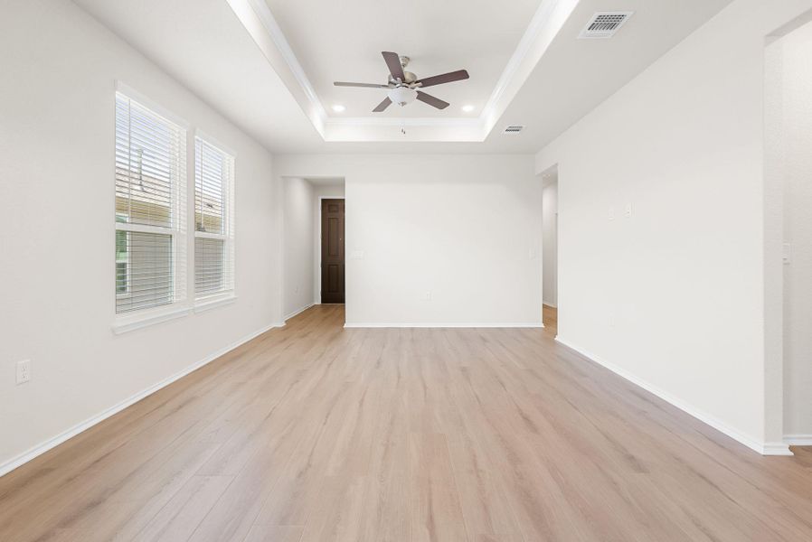 A generously sized interior living area boasts a decorative tray ceiling and durable laminate flooring. A generously sized interior living area boasts a decorative tray ceiling and durable laminate flooring.