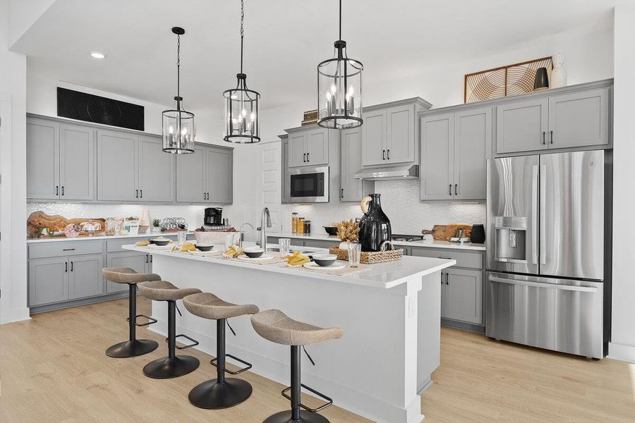 Kitchen with stainless steel appliances, gray cabinetry, light wood finished floors, and a breakfast bar area