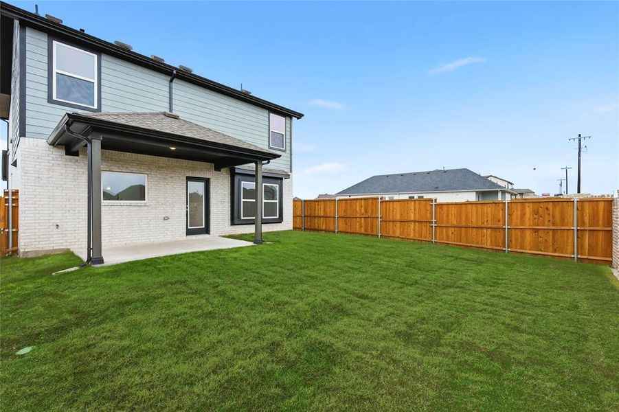 Rear view of property featuring brick siding, a patio area, a fenced backyard, and a shingled roof