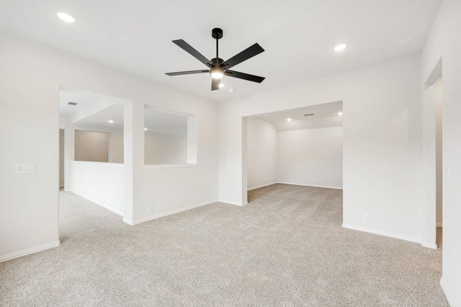 Open living area with carpet flooring, black ceiling fan, and arched doorways leading to adjacent rooms
