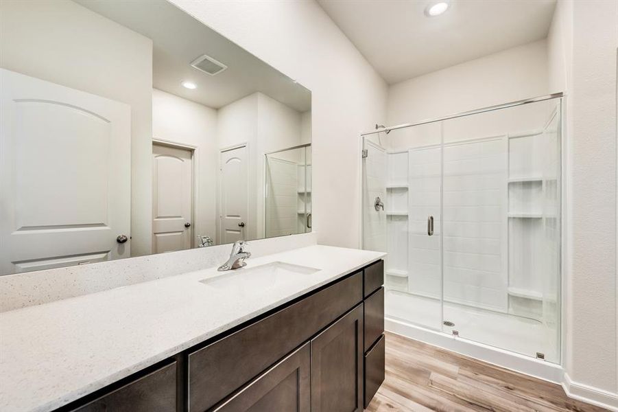 Bathroom with wood-type flooring, a shower with door, toilet, and vanity