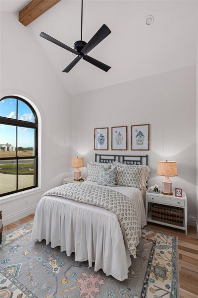 Bedroom with high vaulted ceiling, a ceiling fan, beamed ceiling, and wood finished floors