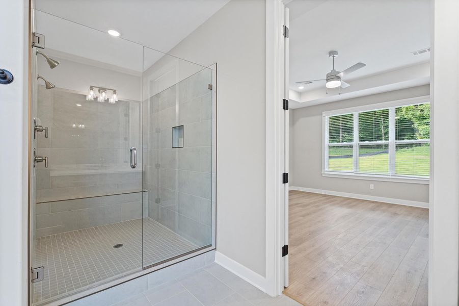 Walk-in shower with clear glass enclosure, multiple showerheads, and integrated bench seating Walk-in shower with clear glass enclosure, multiple showerheads, and integrated bench seating