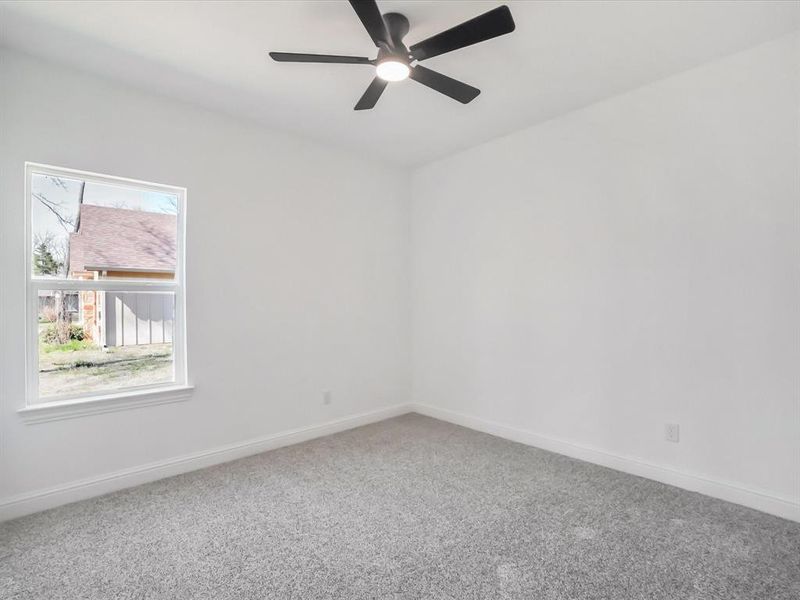 Carpeted spare room featuring baseboards and ceiling fan