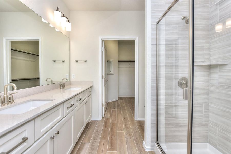 Bathroom with a sink, wood tiled floor, double vanity, and a shower stall