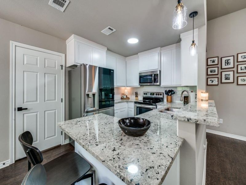 Kitchen featuring appliances with stainless steel finishes, a sink, a peninsula, baseboards, and a breakfast bar Kitchen featuring appliances with stainless steel finishes, a sink, a peninsula, baseboards, and a breakfast bar
