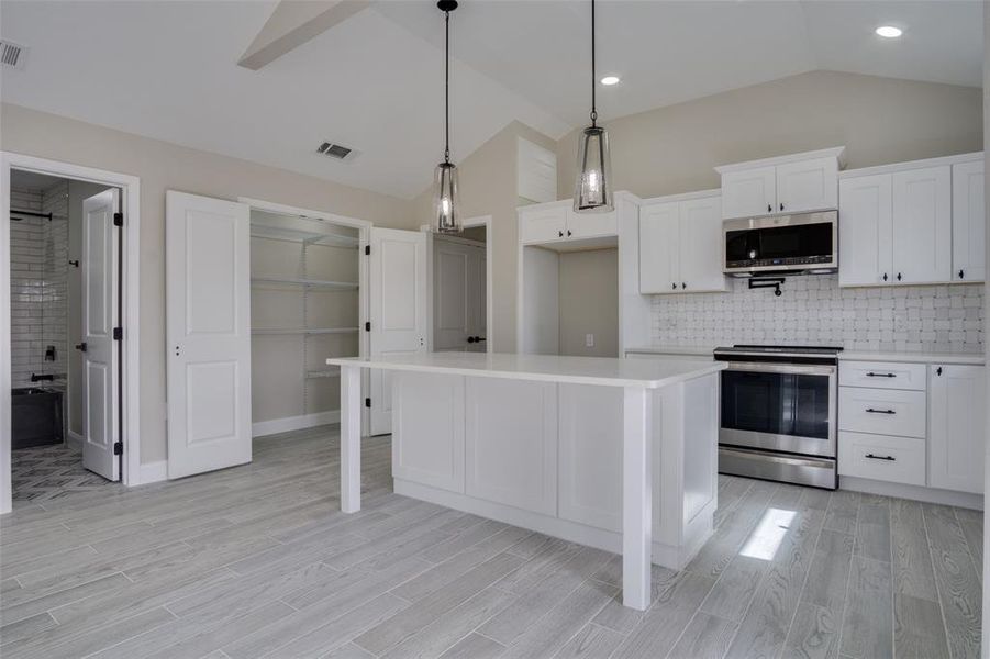 Kitchen with visible vents, stainless steel appliances, white cabinets, light countertops, and wood tiled floor