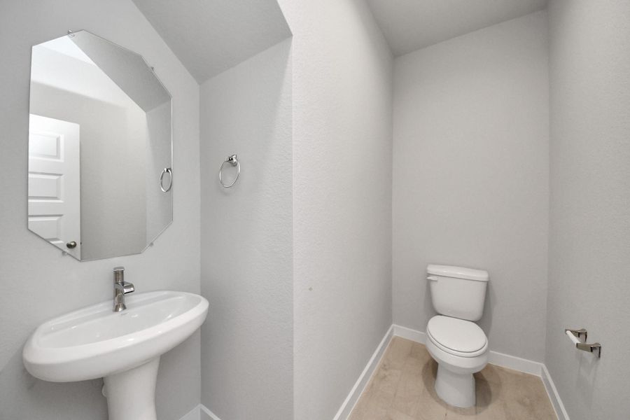 This half bathroom features a stylish pedestal sink, modern hardware, and bright recessed lighting, creating a sleek and inviting space. Sample photo of completed home with similar floor plan. Actual colors and selections may vary.