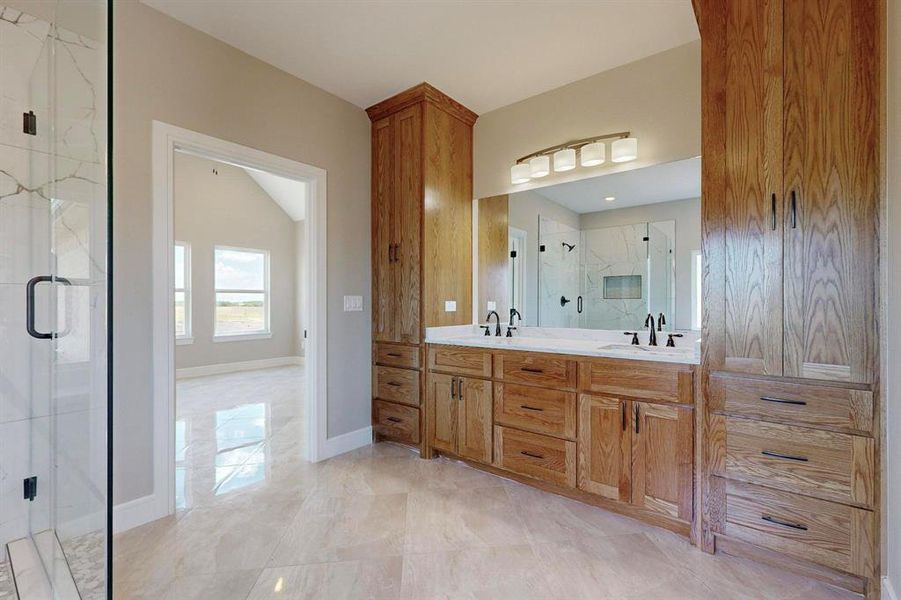 Bathroom featuring tile patterned flooring, double sink vanity, and a shower with door