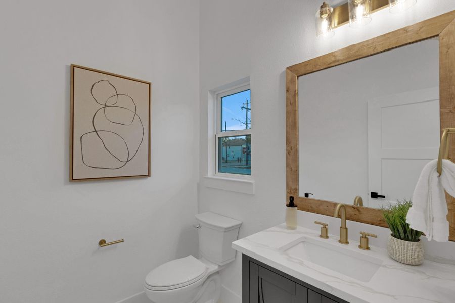 Stylish powder bath with quartz countertop, gold fixtures, and a warm wood-framed mirror for a modern yet elegant touch. Stylish powder bath with quartz countertop, gold fixtures, and a warm wood-framed mirror for a modern yet elegant touch.
