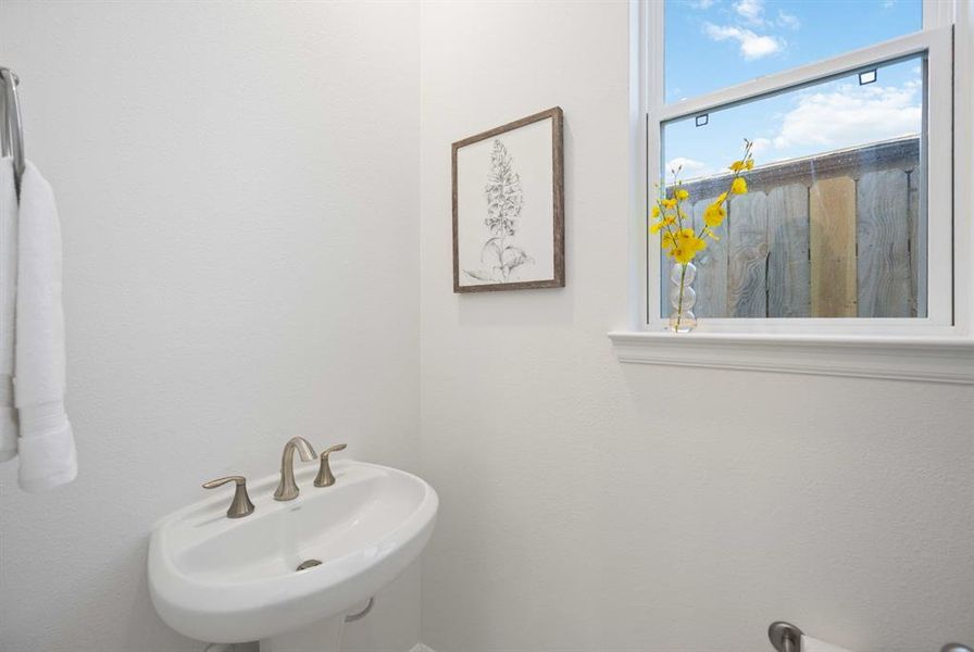 Conveniently tucked under the stairs, this classic powder room with a pedestal sink offers a touch of elegance and privacy.