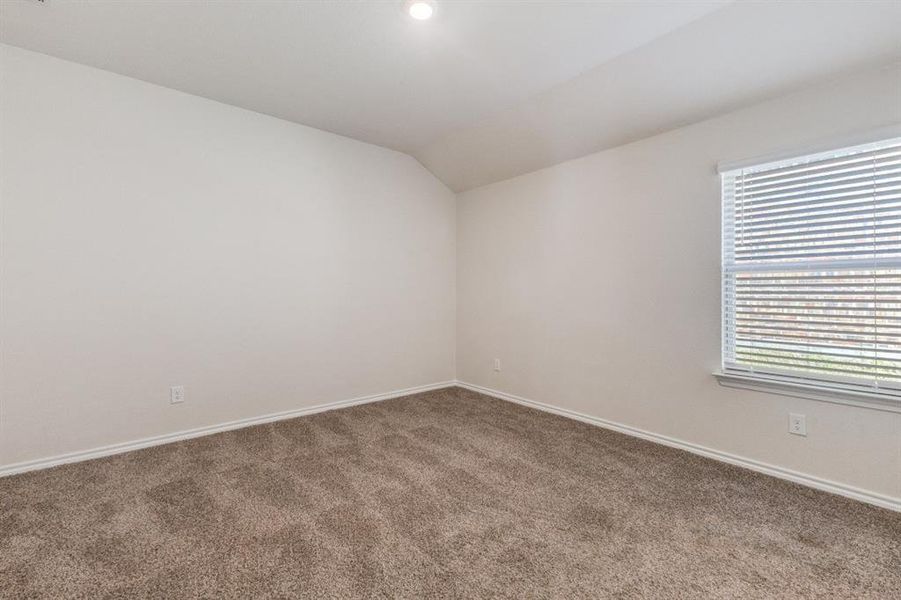 Carpeted spare room featuring vaulted ceiling and baseboards Carpeted spare room featuring vaulted ceiling and baseboards