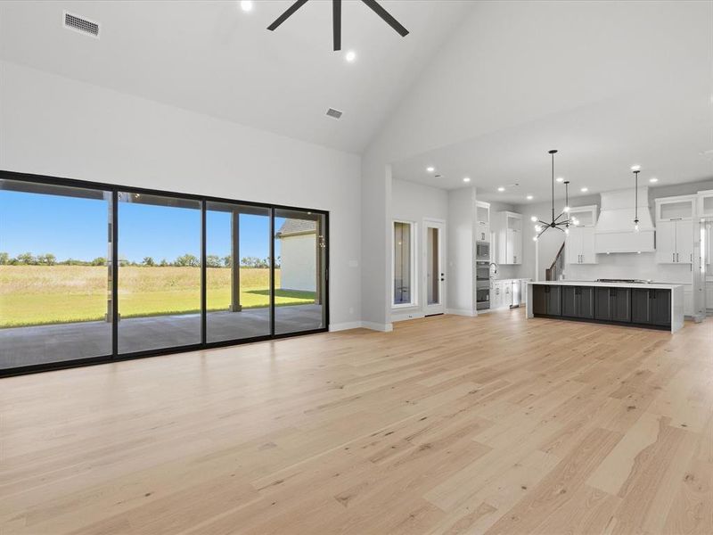 Spacious living area featuring light wood-finish flooring and soaring vaulted ceilings