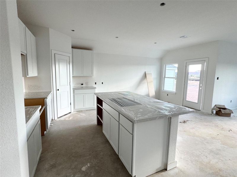 Kitchen with white cabinetry, a kitchen island, and unfinished concrete flooring