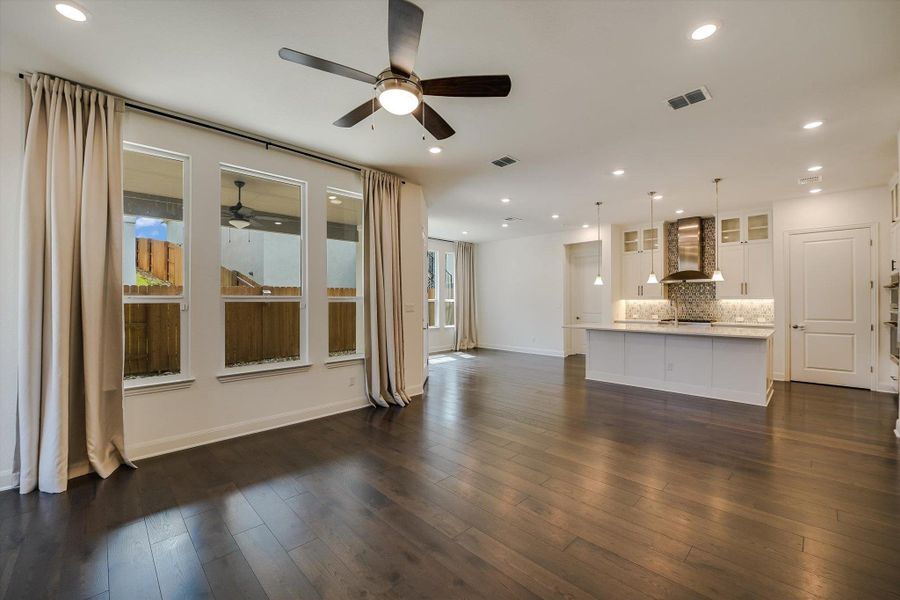 Unfurnished living room featuring recessed lighting, healthy amount of natural light, and dark wood-style floors Unfurnished living room featuring recessed lighting, healthy amount of natural light, and dark wood-style floors