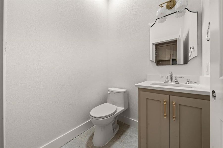 Half bathroom featuring vanity, light tile patterned floors, and a textured wall Half bathroom featuring vanity, light tile patterned floors, and a textured wall