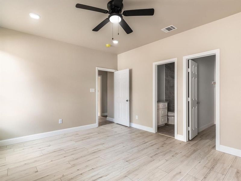 Unfurnished bedroom featuring light wood-type flooring, connected bathroom, a spacious closet, ceiling fan, and recessed lighting Unfurnished bedroom featuring light wood-type flooring, connected bathroom, a spacious closet, ceiling fan, and recessed lighting