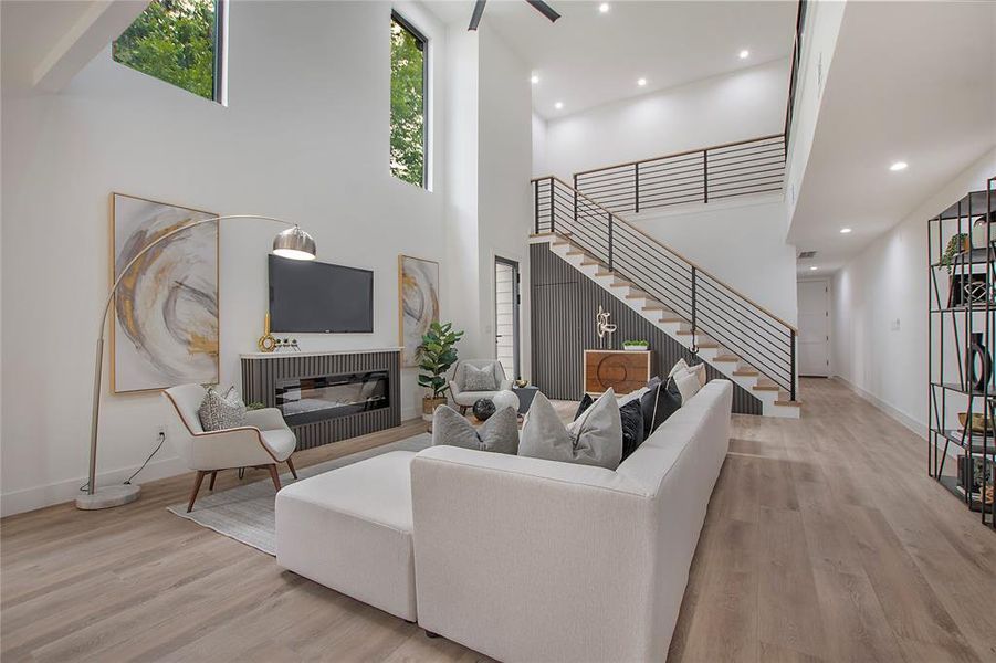 Living room with a high ceiling, ceiling fan, and light hardwood / wood-style flooring