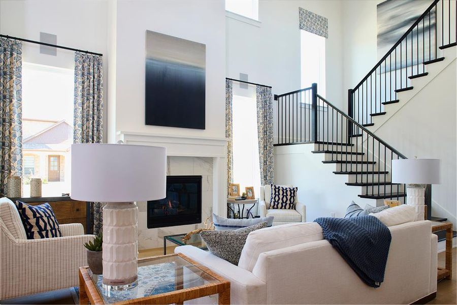 Living area with a towering ceiling, a fireplace, stairs, and wood finished floors