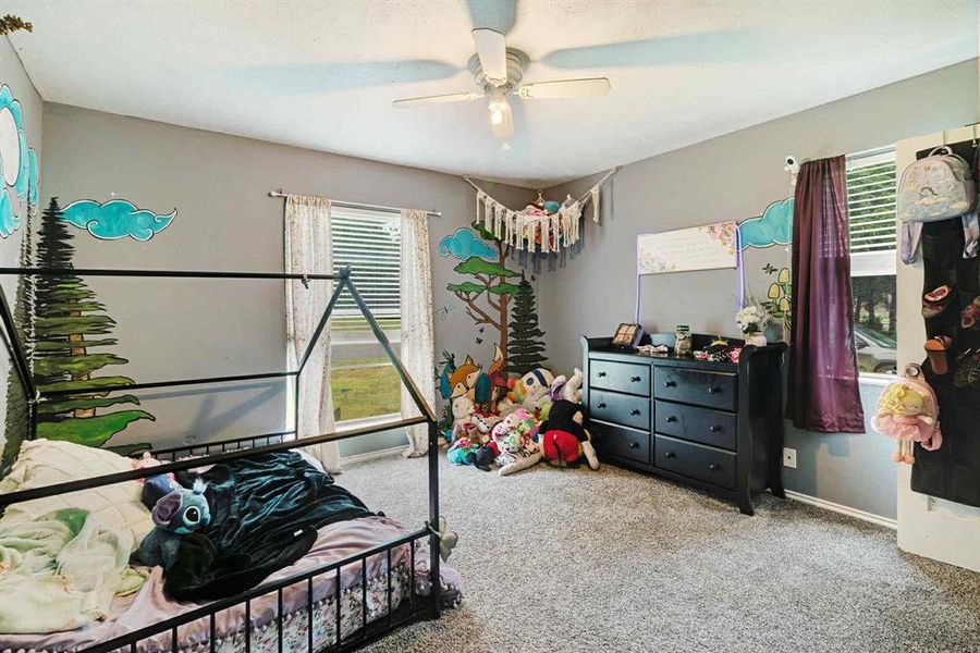 Carpeted bedroom featuring multiple windows and ceiling fan Carpeted bedroom featuring multiple windows and ceiling fan