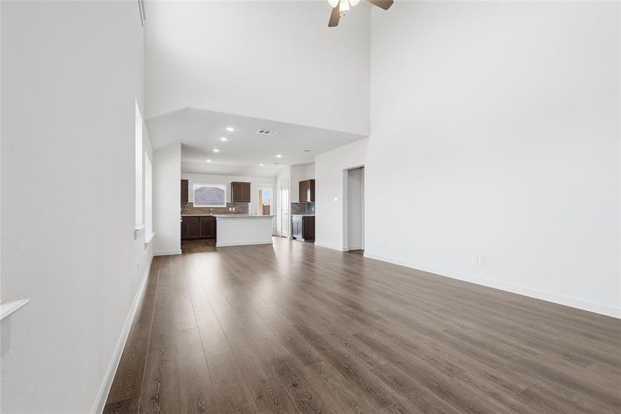 Unfurnished living room featuring a towering ceiling, dark wood-style flooring, ceiling fan, and recessed lighting Unfurnished living room featuring a towering ceiling, dark wood-style flooring, ceiling fan, and recessed lighting