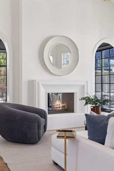 Living room featuring healthy amount of natural light, a lit fireplace, and a high ceiling