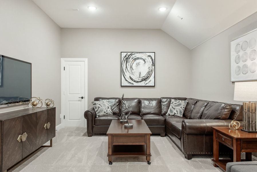 Living room with dark leather sectional sofa, vaulted ceiling, and wall-mounted TV on wood console Living room with dark leather sectional sofa, vaulted ceiling, and wall-mounted TV on wood console