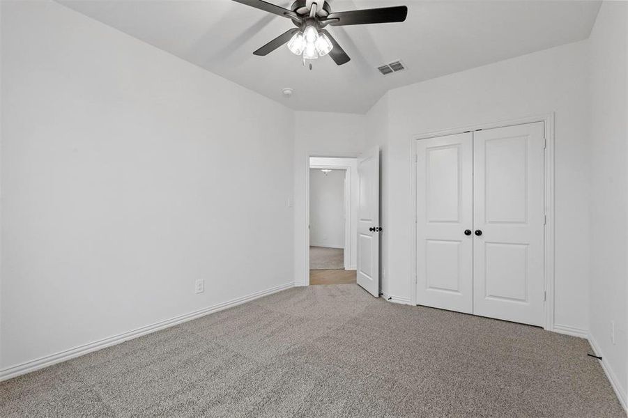 Unfurnished bedroom with ceiling fan, a closet, and light colored carpet