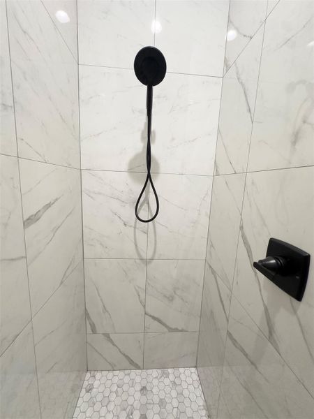 Floor-to-ceiling marble-look tile wraps this shower, complemented by modern matte black fixtures. Floor-to-ceiling marble-look tile wraps this shower, complemented by modern matte black fixtures.