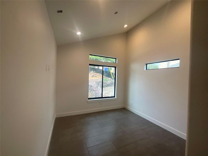 Empty room featuring recessed lighting, high vaulted ceiling, and dark tile patterned flooring Empty room featuring recessed lighting, high vaulted ceiling, and dark tile patterned flooring