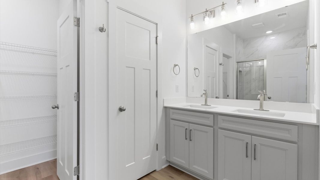 Accomplished design shines in this primary bath with dual vanity and a sleek tiled walk-in shower