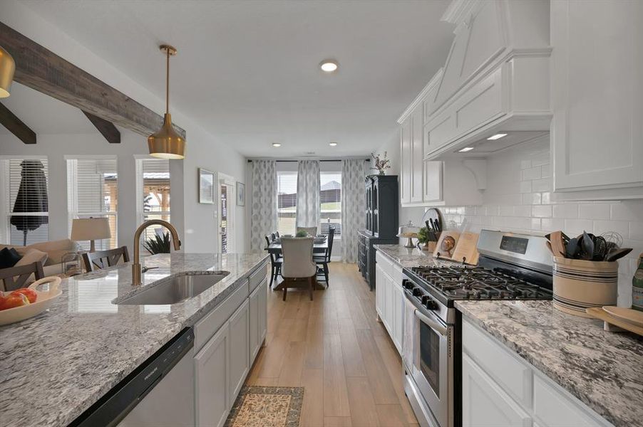 Kitchen with appliances with stainless steel finishes, white cabinetry, light stone countertops, light wood-style flooring, and recessed lighting Kitchen with appliances with stainless steel finishes, white cabinetry, light stone countertops, light wood-style flooring, and recessed lighting