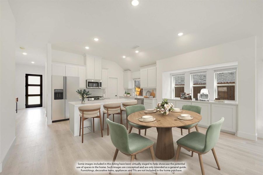 Open-plan kitchen and dining area with white cabinets, round wood table, green chairs, and light hardwood floors Open-plan kitchen and dining area with white cabinets, round wood table, green chairs, and light hardwood floors