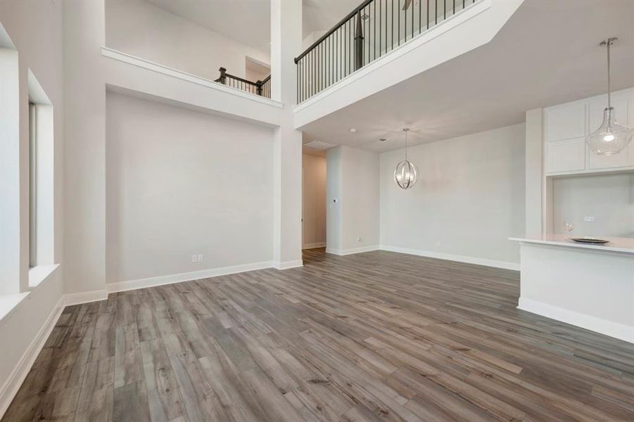 Unfurnished living room with a high ceiling, dark wood-style flooring, and suspended lighting