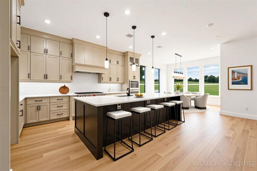 Dual tone kitchen featuring a center island with sink, a breakfast bar area, light wood-type flooring, tasteful backsplash, and dual tone cabinets