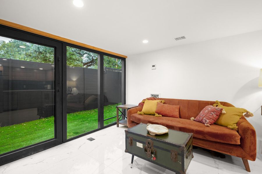 Living room with marble finish flooring, a wall of windows, and recessed lighting