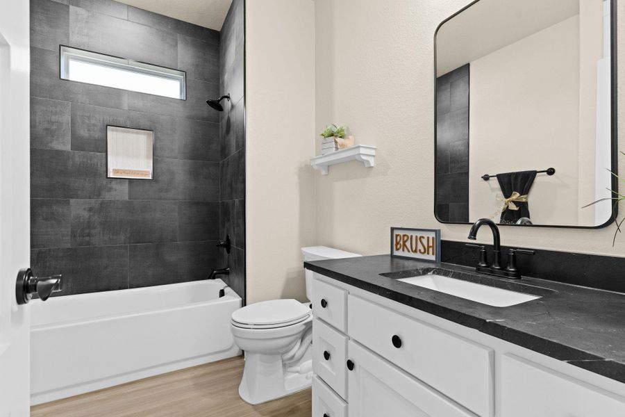 Bathroom with wood finished floors, toilet, bathing tub / shower combination, and vanity Bathroom with wood finished floors, toilet, bathing tub / shower combination, and vanity